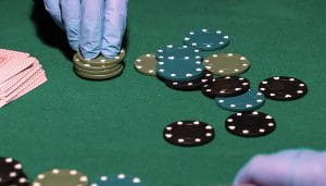 Casino Chips Handled with Gloves Next to Casino Cards on a Poker Table