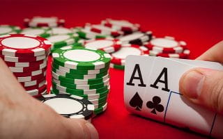 A Two Aces Hand next to Stacks of Chips over a Red Surface